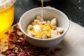 Peeled raw peanuts in a white ceramic bowl poured with thin honey trickle