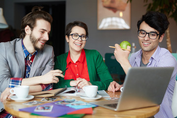 Happy designers looking at online data on laptop monitor