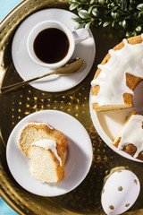 Easter cake, cup of coffee and decorative egg on a golden tray, top view