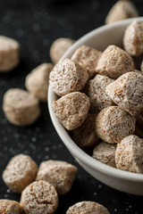 Macro shot of wheat bran in a white ceramic bowl on a black wooden table