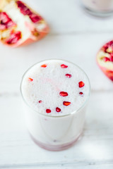 Traditional indian lassi - cold yougurt drink on white table with pomegranate seeds