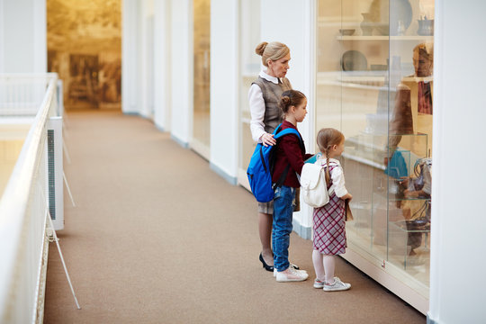Guide of museum showing little visitors obsolete folk objects in display-window