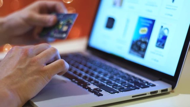 pay online, close up of hands with credit card typing on keyboard at home in the evening