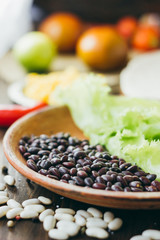 Black beans on brown pottery plate over wooden board.