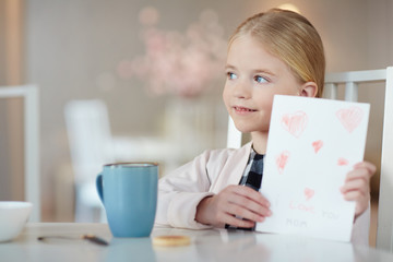 Girl with greeting card sitting by table