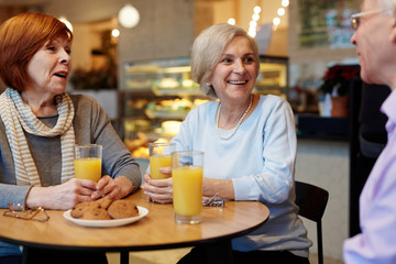 Old buddies sitting by table in cafe and having talk