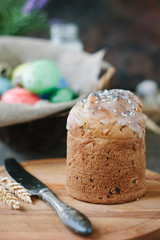 Easter cake standing on board against the basket with easter eggs.