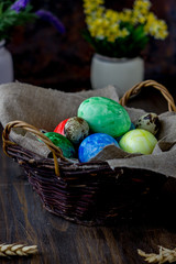 Colored easter eggs on basket over rustic table.