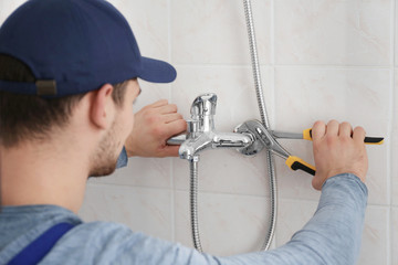 Plumber fixing faucet in bathroom