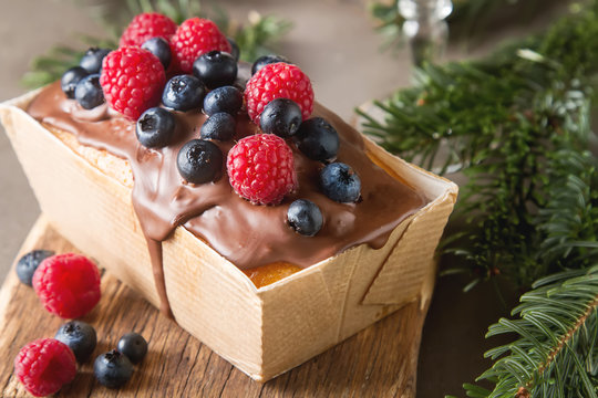 Christmas cake with chocolate frosting, blueberries and raspberries. Dark background.