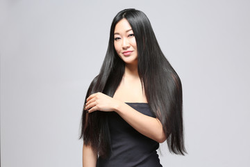 Naklejka premium Beautiful Asian woman with long straight hair on light background