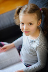 Cute girl of younger school age reads the book.