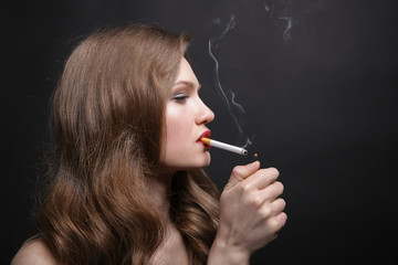 Fototapeta premium Portrait of beautiful woman with cigarette on black background