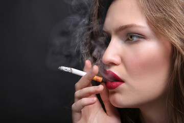 Obraz premium Portrait of beautiful woman with cigarette on black background