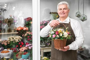 Papier Peint photo Fleuriste Male florist holding basket with flowers in flower shop
