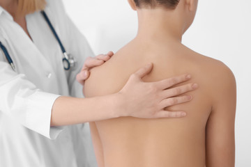 Incorrect posture concept. Physiotherapist examining and correcting boy's back