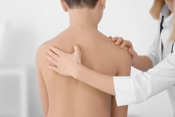 Incorrect posture concept. Physiotherapist examining and correcting boy's back