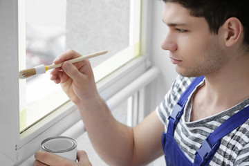 Young worker painting window in office