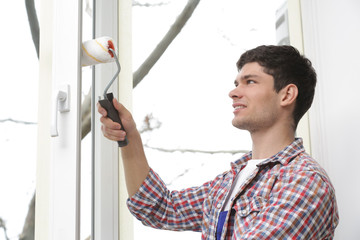 Young man painting window in office