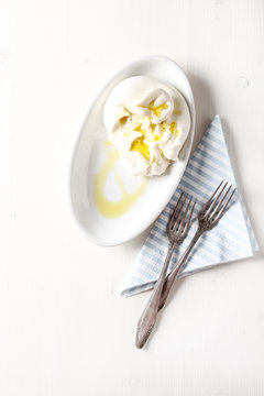 Italian fresh burrata cheese in a ceramic bowl. Light white background.
