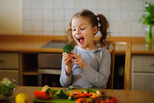 Girl of 8-9 years sits at a kitchen table.