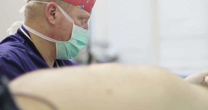 4K Close up. Adult doctor wearing a mask in the operating room.