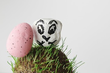 Pink easter egg and bird painted on white stone standing on round grass surface made of vermiculite mineral  - Powered by Adobe