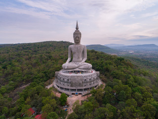 aerial view of Big Buddha sitting image on mountain with blue sky clouds at mukdahan province, Thailand.