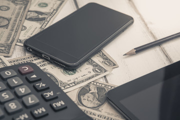 Calculator with american dollars on the wooden table background, finance concept, pencil, phone