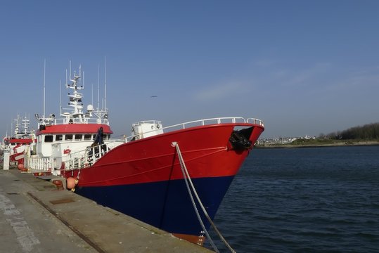 Red fishing boat alongside the wharf at the fishing harbor of Lorient, Brittany France.Horizontal front view 