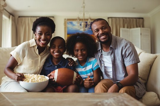 Portrait Of Parents And Kids Watching Television In Living Room