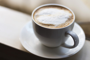 Hot coffee in a white cup is at the window.