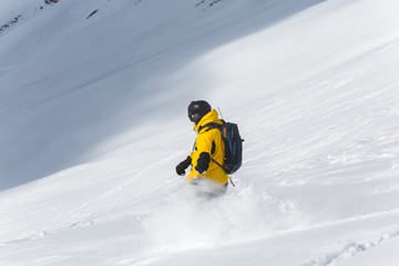 Male snowboarder snowboarding on fresh snow on ski slope on Sunny winter day in the ski resort in Georgia