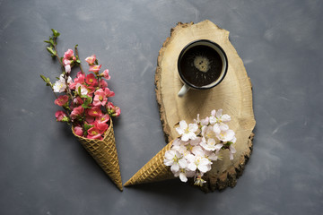 Flowers in ice cream cone and coffee on cement background