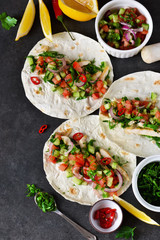 Mexican tacos with filling and guacamole sauce on a black background