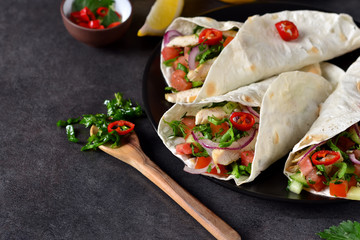Mexican tacos with filling and guacamole sauce on a black background