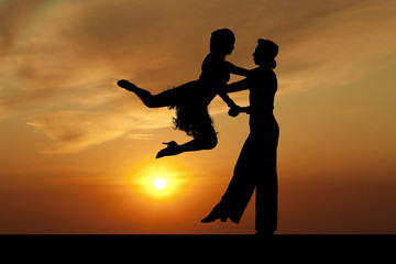 Silhouette couple in the active ballroom dance on sunset