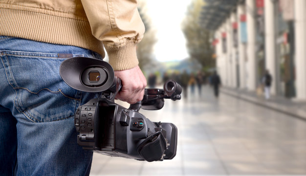 cameraman holding his professional camcorder in the street
