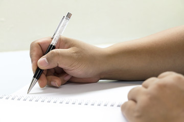 People are holding a pen writing a book.