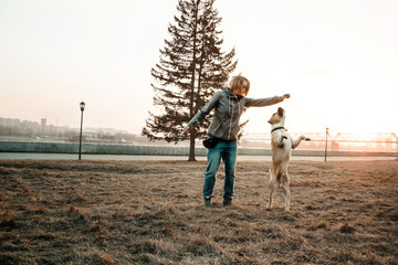Young woman playing with her dog in summer park.