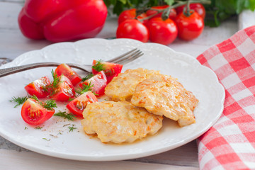 Chicken cutlets chopped with tomatoes on a white plate, selective focus