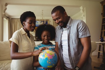 Parents and daughter looking at globe in living room