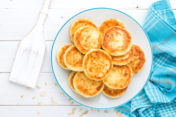 Cottage cheese pancakes with oats, syrniki on white rustic background