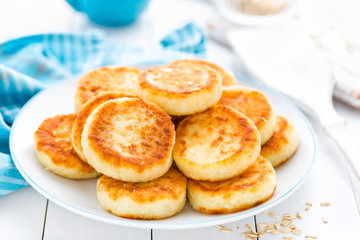 Cottage cheese pancakes with oats, syrniki on white rustic background