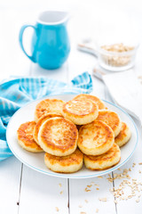Cottage cheese pancakes with oats, syrniki on white rustic background