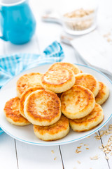 Cottage cheese pancakes with oats, syrniki on white rustic background