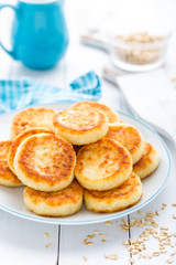 Cottage cheese pancakes with oats, syrniki on white rustic background