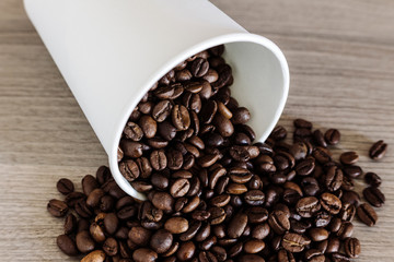 Paper cup and coffee beans on the wooden background