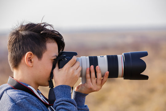 Fototapeta Young male photographer with telephoto in nature