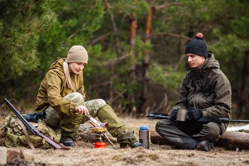 Photo sur Aluminium Chasser .Deux chasseurs mangent ensemble dans la forêt. Concept de bushcraft, de chasse et de personnes